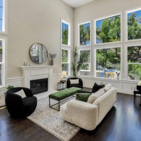 Soaring two-story ceilings and a wall of windows fill the living room with natural light, anchored by a classic fireplace and rich hardwood floors. Soaring two-story ceilings and a wall of windows fill the living room with natural light, anchored by a classic fireplace and rich hardwood floors.