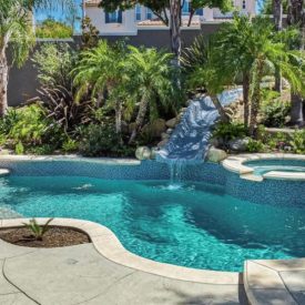 Resort-style backyard with a pool, waterslide, spa, and lush tropical landscaping — a private retreat at home. Resort-style backyard with a pool, waterslide, spa, and lush tropical landscaping — a private retreat at home.